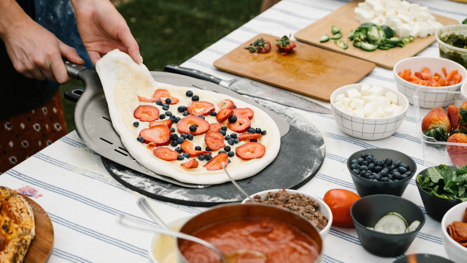 Backyard Pizza Party preparing the pizza with toppings on the side