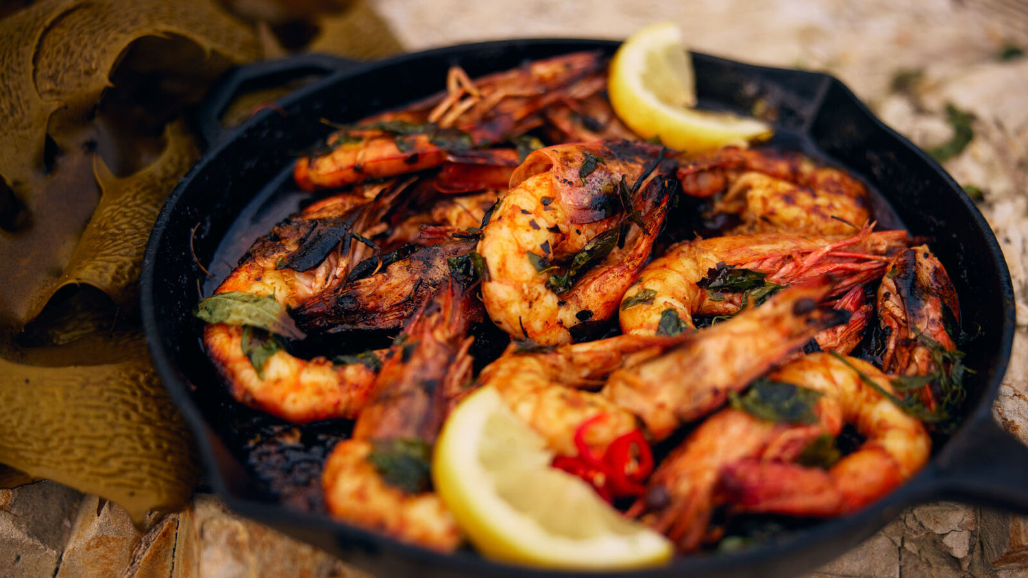 Prawns with lemon in a cast iron pan on the beach recipe poster image