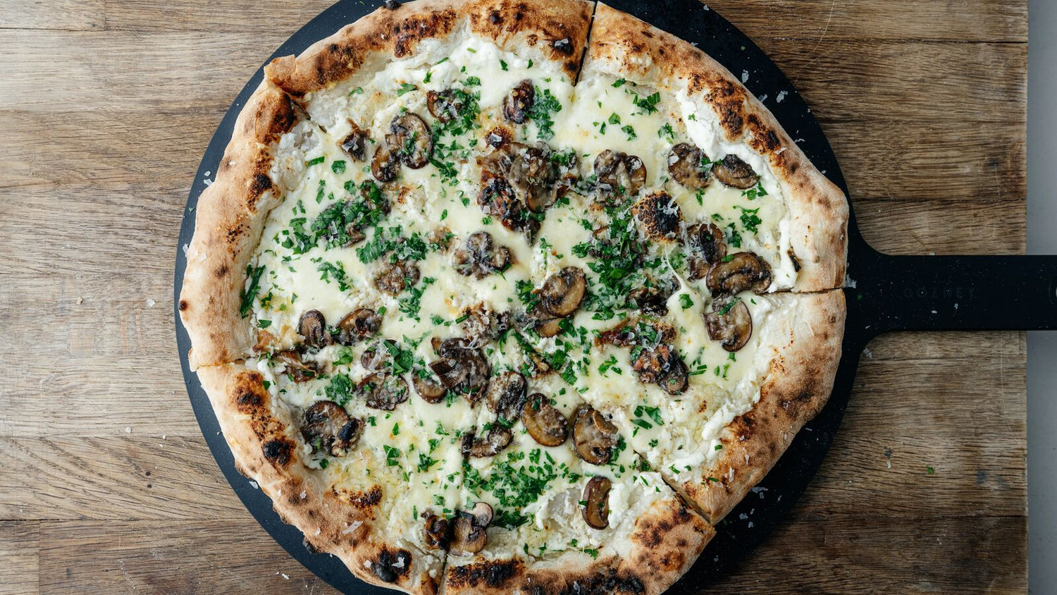 Roasted Mushroom Pizza Bianca on a pizza server on a cutting board recipe poster image
