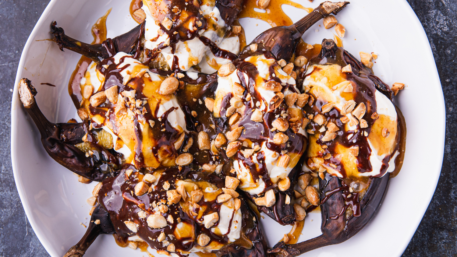 Bananas with chocolate and caramel drizzled over top on a plate recipe poster image
